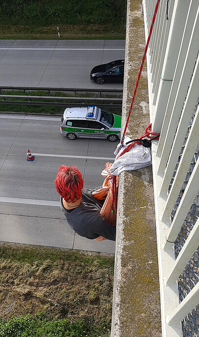 Eine Aktivistin hängt unter einer Brücke über der A94. Eine Aktivistin hängt unter einer Brücke über der A94.