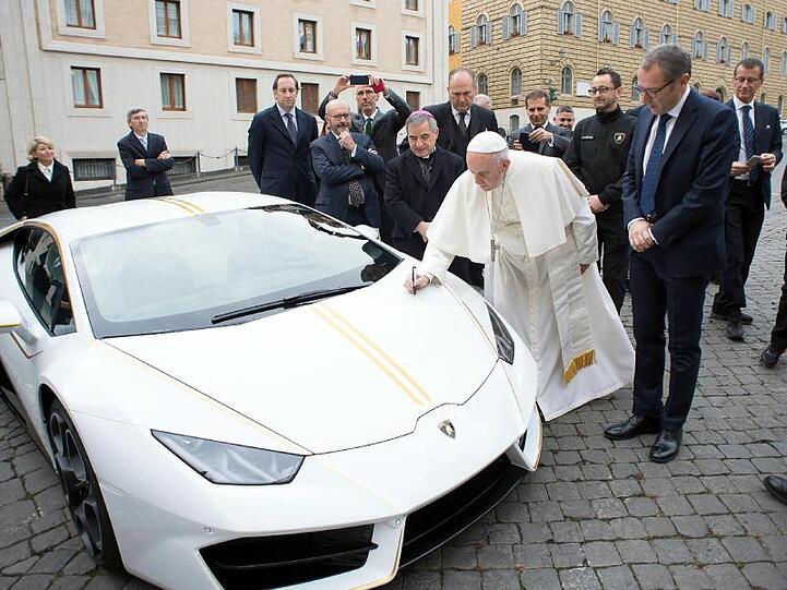 Papst Franziskus signiert den weißen Lamborghini, der ihm vom italienischen Sportwagenhersteller geschenkt wurde.