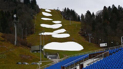 Nur kleine Schneeflecken sind im Skistadion von Garmisch-Partenkirchen (Bayern) zu sehen. Foto: Hartmut Reeh/dpa/Archivbild