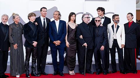 Guillermo del Toro (mit Gehstock) auf dem roten Teppich mit seinen "Frankenstein"-Stars.