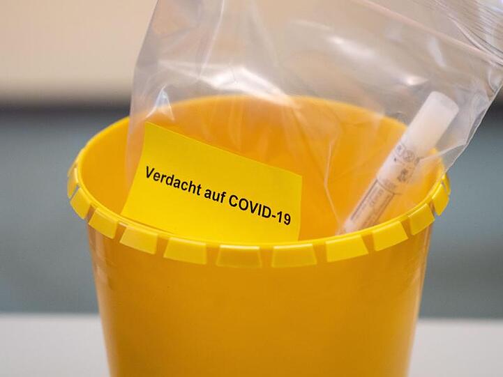 Ein Teströhrchen liegt in einer Tüte mit der Aufschrift "Verdacht auf COVID-19". (Symbolbild).