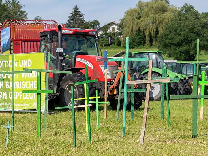 Holzkreuze und Traktoren von demonstrierenden Landwirten stehen von der Autobahnabfahrt bis zur Ortschaft Prien. Foto: Peter Kneffel/dpa