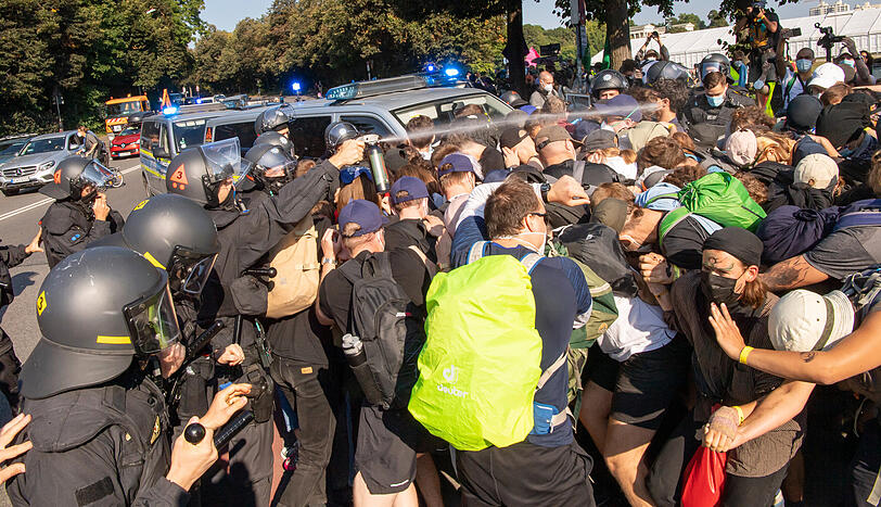 Ein Beamter der Polizei sprüht Pfefferspray in Richtung der Demonstranten.