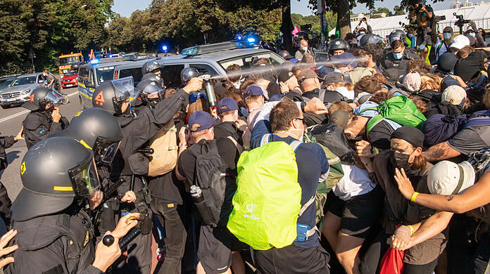 Ein Beamter der Polizei sprüht Pfefferspray in Richtung der Anti-IAA-Demonstranten.
