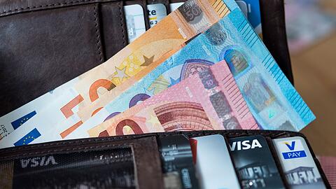 Banknoten und Bankkarten liegen in einer Geldbörse.