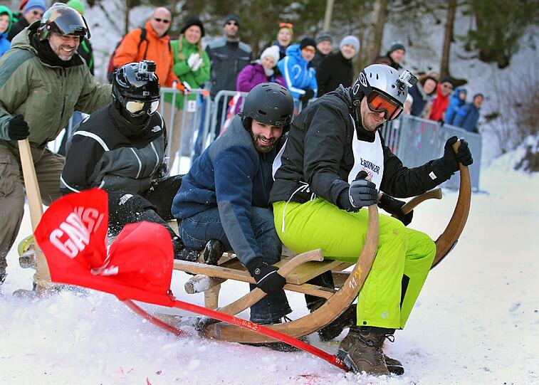 Teilnehmerinnen des traditionellen Hornschlittenrennes fahren in Garmisch-Partenkirchen die Piste hinab.