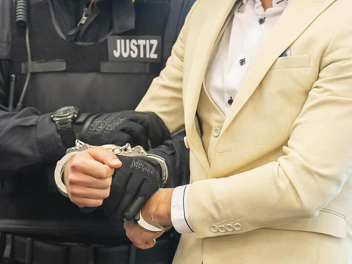 Der Angeklagte wird von einem Justizbeamten in den Gerichtssaal geführt.