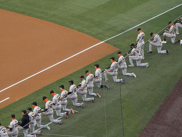 Die Spieler San Francisco Giants knien während einer Schweigeminute vor dem MLB-Eröffnungsspiel.