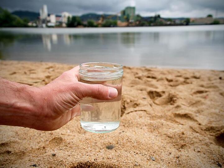 Ein Glas mit Wasser aus dem Sander Baggersee: Nahezu alle Badeseen in Bayern haben eine gute oder sehr gute Wasserqualität.