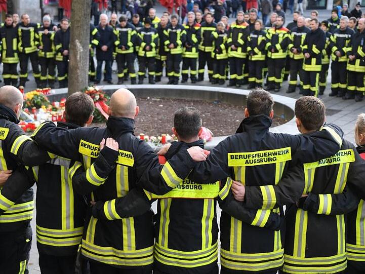 Mitglieder der Berufsfeuerwehr trauern nach der Gewalttat am Königsplatz in Augsburg.