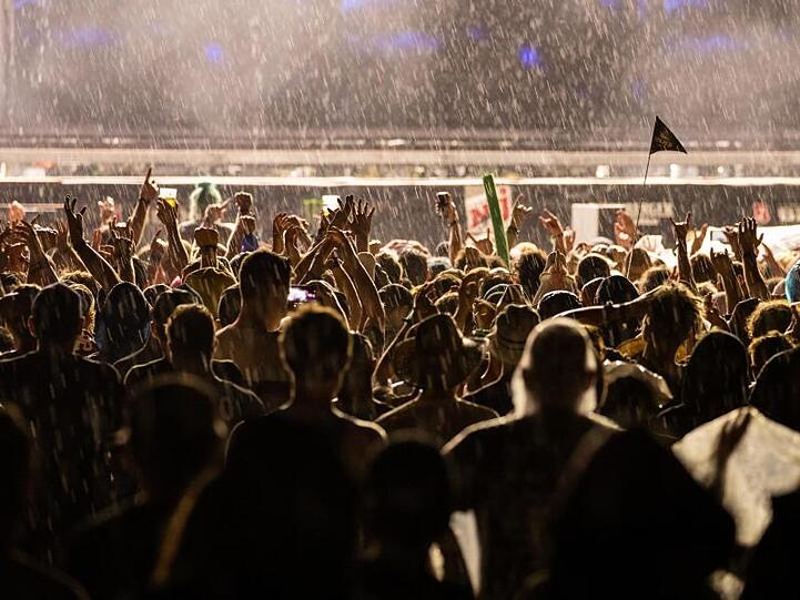 Besucher des Open-Air-Festivals "Rock im Park" verfolgen im Regen ein Konzert. Foto: Daniel Karmann