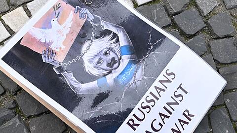 Ein Schild mit der Aufschrift "Russians against war" liegt auf dem Odeonsplatz in München auf dem Boden.