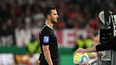 Schiedsrichter Daniel Schlager überprüft eine Szene am Bildschirm auf Handspiel.