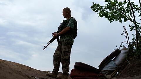 Ein ukrainischer Soldat hält in der Region Donezk Wache vor seinem Zelt.
