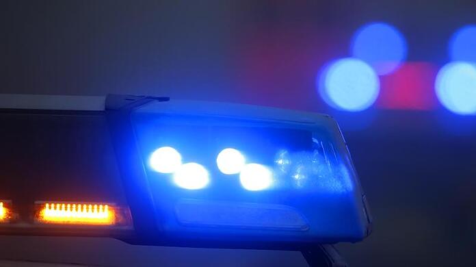 Ein Polizeiauto mit eingeschaltetem Blaulicht steht an einer Unfallstelle.