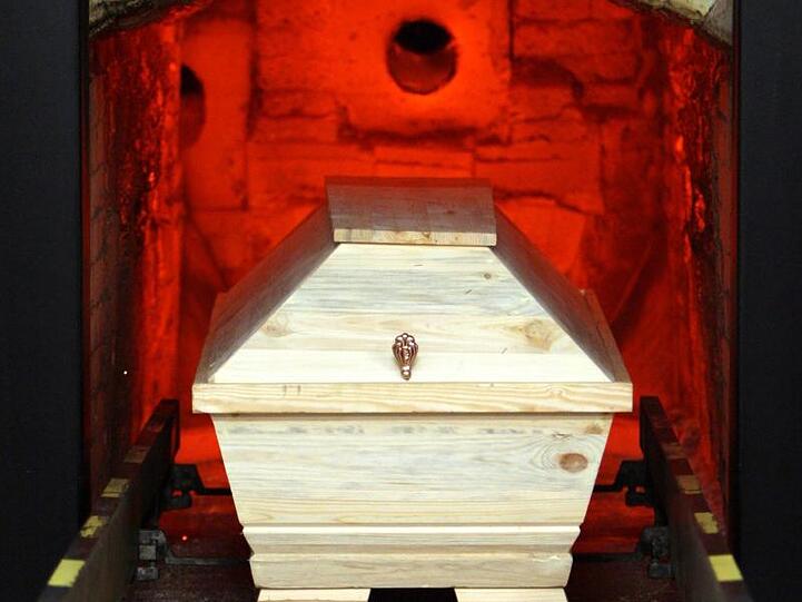 Ein Sarg wird im Krematorium in einen Ofen gefahren. Foto: Kay Nietfeld/dpa/Archivbild