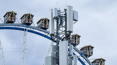 Ein 5G-Mobilfunkmast steht auf dem Oktoberfestgelände vor einem Riesenrad.