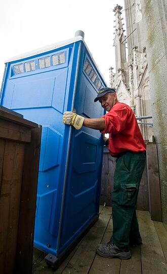 Der Maschinist Oswald Moser haelt am Dienstag (12.06.12) in Regensburg auf dem Dom ein Toilettenhaeuschen.
