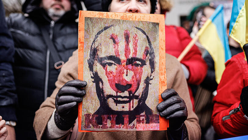 Ein Demonstrant hält ein Plakat mit dem Bild des russischen Präsidenten Wladimir Putin - darauf steht "Killer" (Mörder).