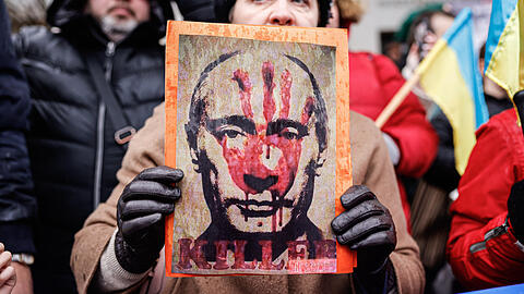 Ein Demonstrant hält ein Plakat mit dem Bild des russischen Präsidenten Wladimir Putin - darauf steht "Killer" (Mörder).