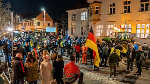 Demonstranten mit Deutschlandfahnen und Traktoren protestieren vor einer Parteiversammlung der Grünen.