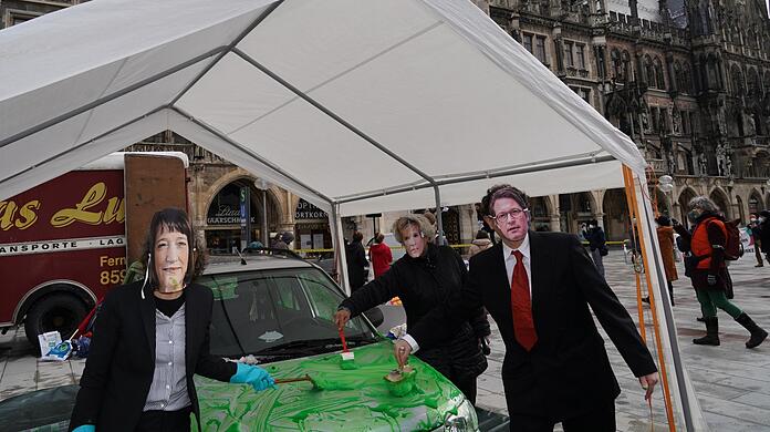 Protest am Rathaus: Verkleidete Aktivisten bemalen ein Auto mit grüner Farbe, um auf sogenanntes "Greenwashing" (Vorgeben, umweltfreundlich zu sein, ohne das zu erfüllen" aufmerksam zu machen.