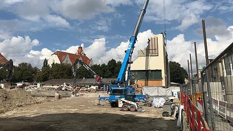 Hier schiebt dieser Kranarm die Staub-Schutzwand vors Gebäude.