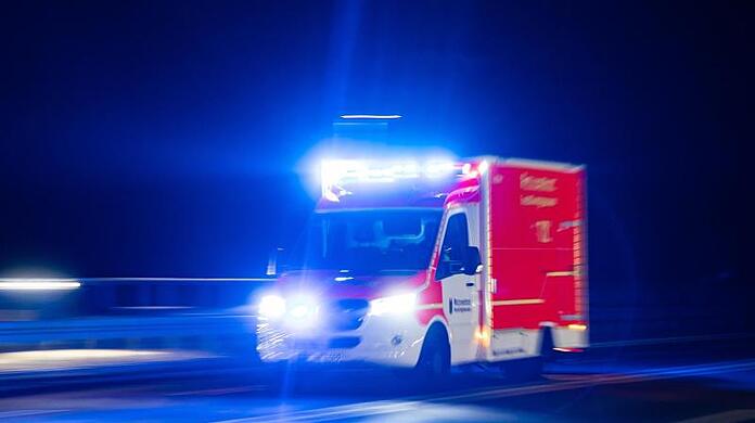 Ein Rettungswagen der Feuerwehr fährt mit Blaulicht durch eine Straße.