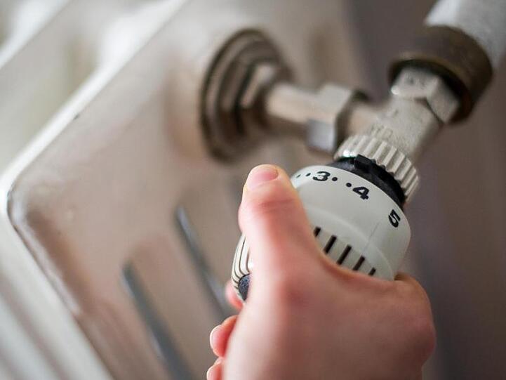 Eine Frau am Thermostat einer Heizung. Foto: Ole Spata/Archiv