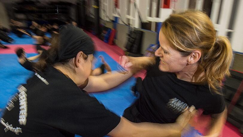 Eine Trainerin für Krav Maga übt in einem Studio mit einer Frau die Abwehr eines Angriffs. Eine Trainerin für Krav Maga übt in einem Studio mit einer Frau die Abwehr eines Angriffs.