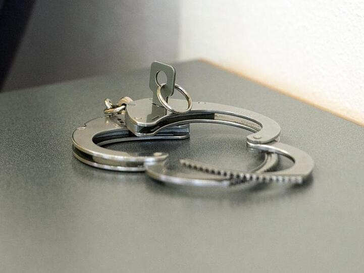 Handschellen liegen auf einem Tisch. Foto: Armin Weigel/dpa/Symbolbild