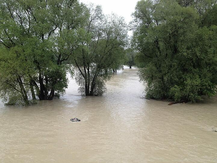 Der Metallkasten, in dem die Isar-Griller ihre Rückstände entsorgen sollen, ragt kaum mehr aus der braunen Brühe heraus...