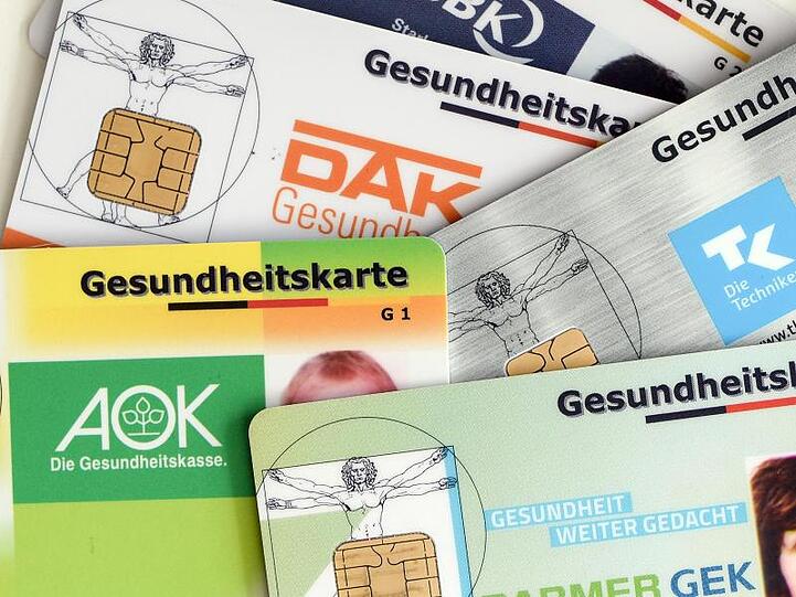 Gesundheitskarten verschiedener Krankenkassen liegen auf einem Tisch.