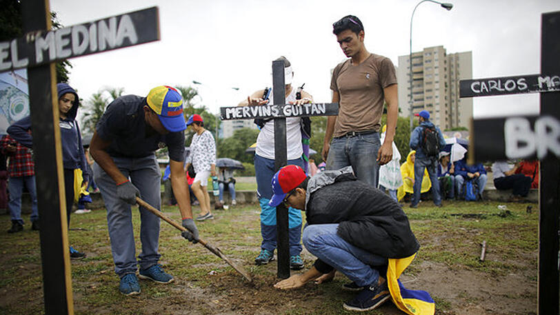 Regierungskritiker stellen in Caracas Kreuze mit Namen der Menschen auf, die bei Protesten gegen die Regierung ums Leben gekommen sind.