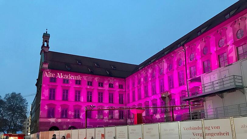 Die Alte Akademie: In der Dämmerung beginnt ein Farbenspiel. Mal tanzen weiße Schneeflocken-Spots auf der Fassade, mal strahle sie in pink.