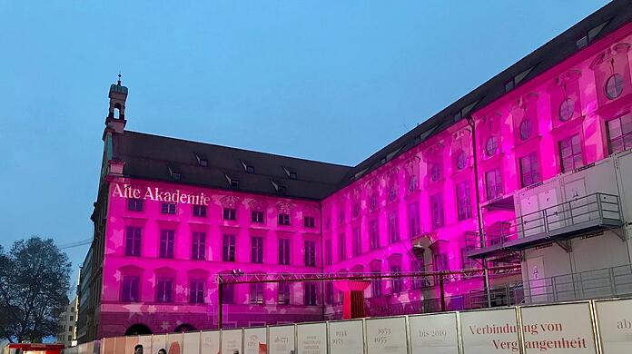 Die Alte Akademie: In der Dämmerung beginnt ein Farbenspiel. Mal tanzen weiße Schneeflocken-Spots auf der Fassade, mal strahle sie in pink.