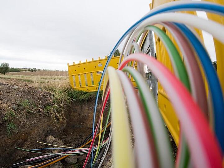 Leerrohre für Glasfaserleitungen für schnelles Internet liegen an einer Landstraße in der Baugrube. Foto: Julian Stratenschulte