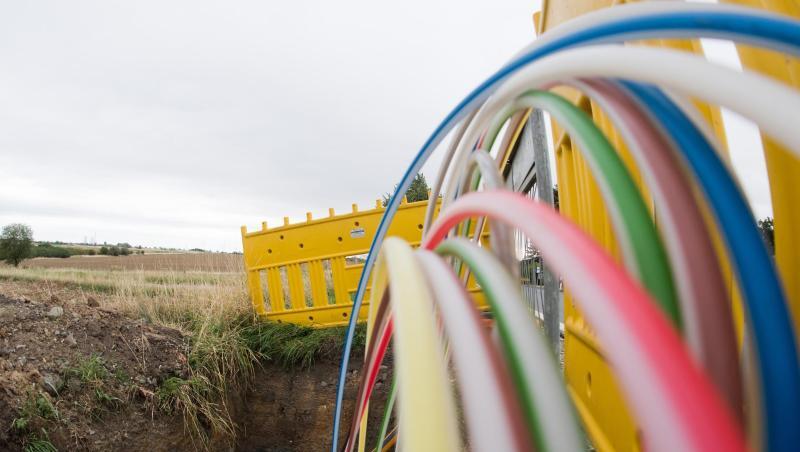 Leerrohre für Glasfaserleitungen für schnelles Internet liegen an einer Landstraße in der Baugrube. Foto: Julian Stratenschulte