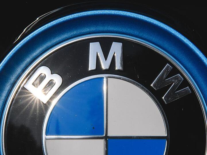 Die Sonne spiegelt sich in einem Logo des Autoherstellers BMW. Foto: Sebastian Gollnow/dpa/Archivbild