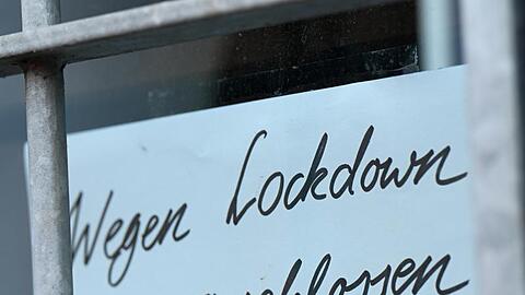 Ein Zettel mit der Aufschrift "Wegen Corona geschlossen" h&auml;ngt am Schaufenster eines Gesch&auml;fts in Seligenstadt.