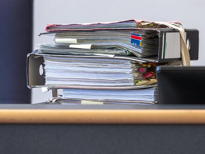 Akten liegen auf einem Tisch. Foto: Armin Weigel/dpa/Symbolbild