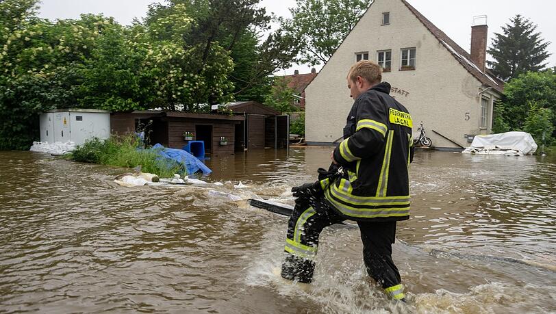 Ein Feuerwehrmann stapft in Wertingen im Landkreis Dilligen an der Donau durchs Wasser.