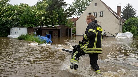Ein Feuerwehrmann stapft in Wertingen im Landkreis Dilligen an der Donau durchs Wasser.