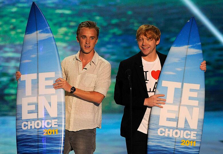 Auch die "Harry Potter"-Stars Tom Felton (links)und Rupert Grint, alias Draco Malfoy und Ron Weasley, schleppen Surfbretter von der Bühne. Glückwunsch!