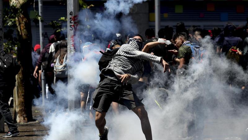Ein Demonstrant wirft bei Protesten in Santiago de Chile eine Tränengasgranate zurück auf Polizisten. Ein Demonstrant wirft bei Protesten in Santiago de Chile eine Tränengasgranate zurück auf Polizisten.