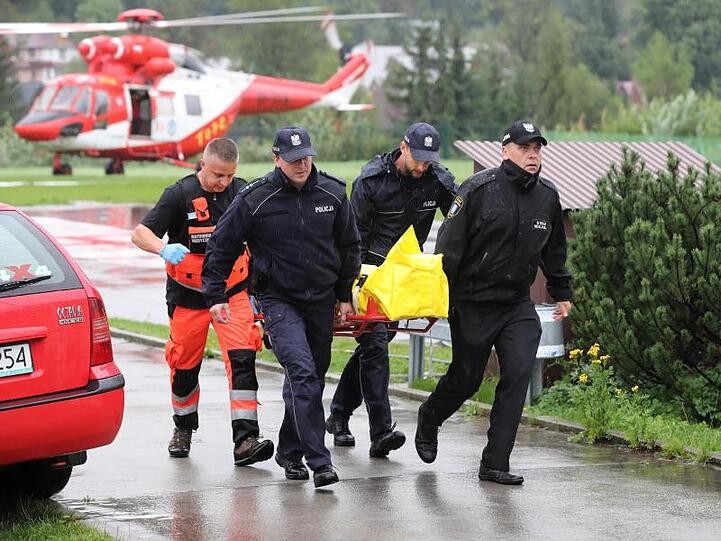 Polizisten tragen in Zakopane einen verletzten Touristen zu einem Krankenwagen.