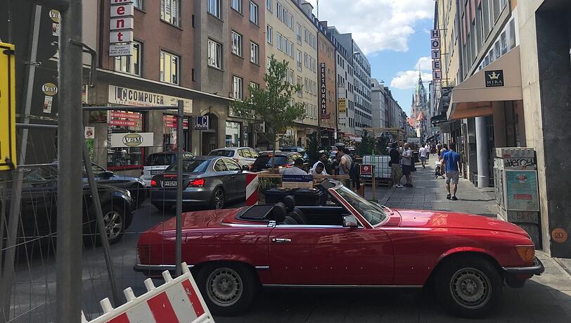 Die Landwehrstraße hat jetzt Parklets (statt Parkplätzen), in die man sich setzen und Brotzeit machen kann. Mancher Autofahrer nimmt's gelassen - und stellt sich halt in die Einfahrt.