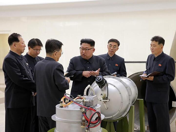 Nordkoreas Staatschef Kim Jong Un neben einem Sprengkopf.