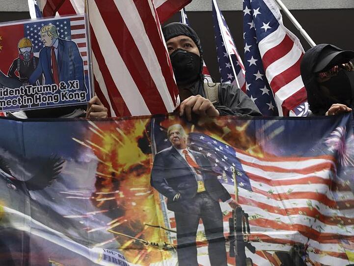 Demonstranten schwenken in Hongkong US-Fahnen und Plakate.