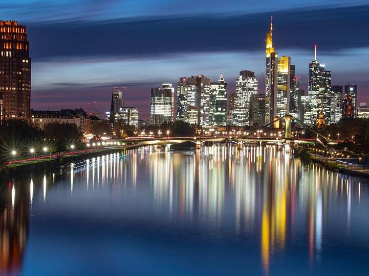 Die Hochhäuser der Bankenskyline spiegeln sich im Wasser des Main.